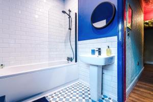 a bathroom with a sink and a tub and a mirror at Spacious and Modern 5 BR House in Manchester