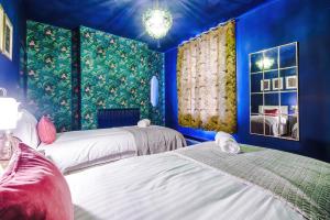 two beds in a room with blue walls at Spacious and Modern 5 BR House in Manchester