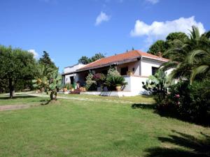 una casa con un césped verde delante de ella en Villa Tullio, en Capo dʼOrlando