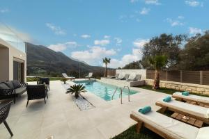a backyard with a swimming pool and a patio with furniture at Villa Silentium Olia by PosarelliVillas in Aryiroúpolis