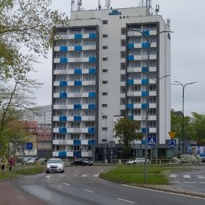a large building with blue windows in front of a road at Apartament Nad Parsętą 502 in Kołobrzeg