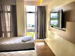 a bedroom with a bed and a flat screen tv at Double Happiness Hotel in Seri Manjung