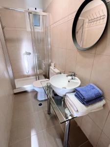 een badkamer met een wastafel, een toilet en een spiegel bij Stylish loft with fireplace, jacuzzi and gym in Agios Nikolaos