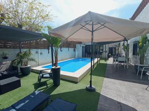 una piscina con sombrilla, mesa y sillas en Edard's Great House, en Castelldefels