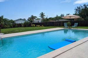 una piscina con sombrilla y 2 sillas en Pool home on the Bay, large private yard near AMI en Bradenton