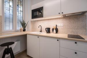 uma cozinha com armários brancos e um lavatório em KL35- Boutique Apartments, Best Location. By BQA em Budapeste