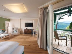 a bedroom with a bed and a balcony with a view at Romantik SPA Hotel Seefischer in Döbriach