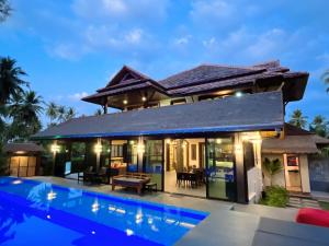 a villa with a swimming pool in front of a house at Coral Beach Pool Villa Khao Lak - SHA Extra Plus in Khao Lak