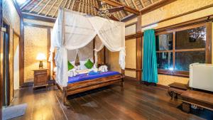 吉利特拉旺安的住宿－Alam Gili Trawangan by Mahaputra，一间卧室设有一张天蓬床和一台电视机。