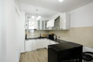 een keuken met witte kasten en een zwart aanrecht bij Isaran Apartament with Panoramic City View in Braşov