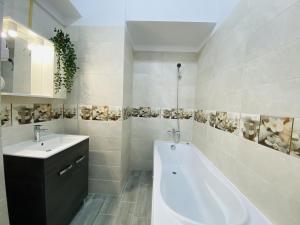 La salle de bains blanche est pourvue d'une baignoire et d'un lavabo. dans l'établissement New City Studios with Balcony, à Bucarest