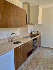 a kitchen with wooden cabinets and a sink at Hôtel La Falaise in Cotignac +58 photos