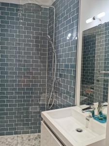bagno con lavandino e doccia con piastrelle blu di Chambre meublée indépendante a Charbonnières-les-Bains