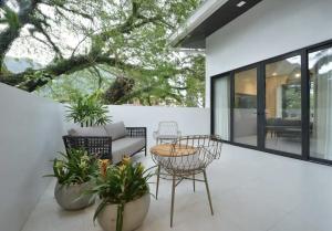 une terrasse avec un canapé, des chaises et des plantes dans l'établissement The Apartments at El Nido, à El Nido