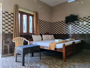 - une chambre avec un lit, une télévision et une chaise dans l'établissement Blue Leaf Residency, à Rameswaram