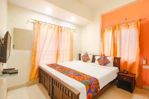 a bedroom with a large bed with orange curtains at FabHotel Corner Courtyard in Kondapur