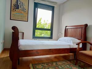 1 dormitorio con cama de madera y ventana en Babilonia, apartamento en Llanes tranquilo y céntrico a 150m de la playa del Sablón, en Llanes