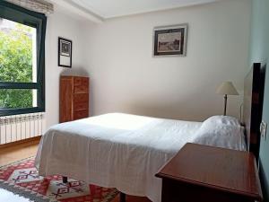 a bedroom with a bed and a table and a window at Babilonia, apartamento en Llanes tranquilo y céntrico a 150m de la playa del Sablón in Llanes