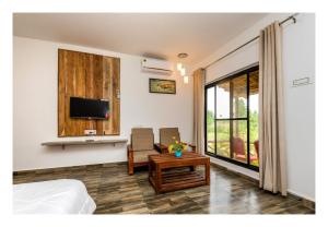 a bedroom with a bed and a tv and a table at Grand Narmada Homestay Resort-Bandhavgarh in Tāla