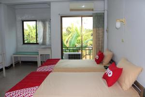 a bedroom with two beds with red pillows and a window at OYO 75420 Howto Hotel in Chiang Mai