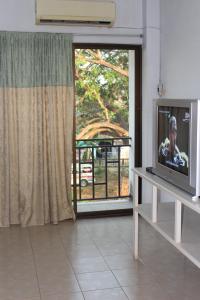 a living room with a television and a sliding glass door at OYO 75420 Howto Hotel in Chiang Mai