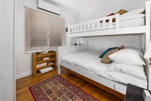 a bedroom with a white bunk bed and a rug at Cosy Cottage Above the Hawkesbury w/ Jetty in Mooney Mooney
