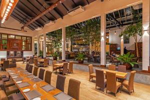 een restaurant met houten tafels en stoelen en een bar bij Birds Resort Hambantota in Hambantota