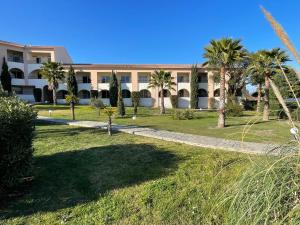 a large building with palm trees in front of it at Superbe T2 Sognu di Mare in Linguizzetta