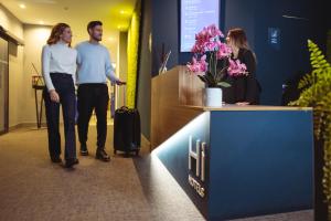Hi Hotel - Wellness & Spa في ترينتو: رجل وامرأة يقفان في مكتب الاستقبال