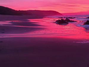 a sunset on the beach with a pink at Linga Futhi Beach Cottages in Port St Johns