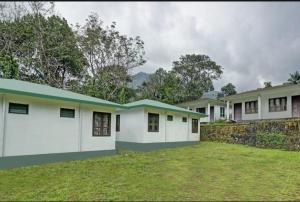 uma casa com paredes brancas e um telhado verde em Mountain View cottage Mankulam em Munnar