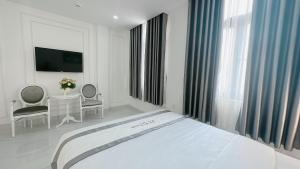 a white bedroom with a bed and a table and chairs at PARIS HOTEL in Danang +20 photos