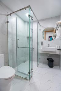 La salle de bains est pourvue d'une douche en verre et de toilettes. dans l'établissement TMS Beachfront Apartment Quy Nhon Bay, à Quy Nhơn