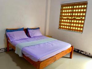 a bedroom with a bed with purple sheets and a window at Felcordz Nature Farm & Resort 