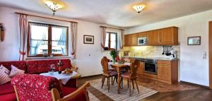 cocina y sala de estar con sofá rojo y mesa en Landhaus Bergkristall - Sommer Bergbahnen inklusive en Oberstdorf