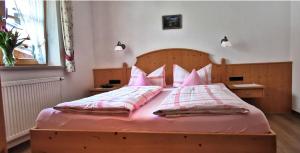 sypialnia z drewnianym łóżkiem z różową pościelą i poduszkami w obiekcie Landhaus Bergkristall - Sommer Bergbahnen inklusive w mieście Oberstdorf