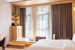 a hotel room with a bed and a window at Euphoria Hotel Lukang in Lugang