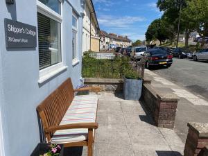 un banco sentado en la acera fuera de un edificio en Skipper’s Cottage - Perfect for Cardiff & Penarth, en Cardiff