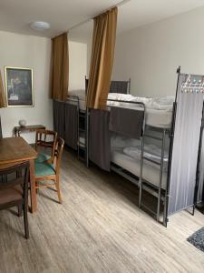 a room with three bunk beds and a table and chairs at Hostel am Ostentor in Regensburg