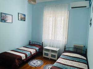 2 camas en una habitación con paredes azules y ventana en Sea voyage, en Nauplia