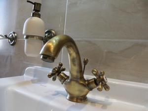 a bathroom sink with a brass faucet and a light at Edinburgh in Mariánské Lázně