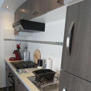 a small kitchen with a stove and a sink at T2 parking à réserver Wi-Fi 10' à pied du port in Vannes