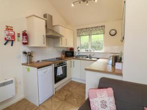 cocina con armarios blancos y encimera en Chalet Log Cabin L12, en Ilfracombe