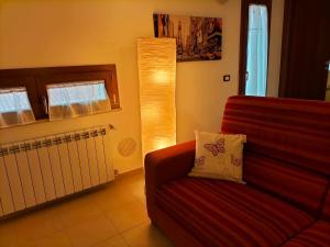 a living room with a red couch and a lamp at Come a casa in LʼAquila