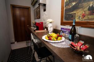 una mesa con una bandeja de fruta y una botella de vino en Camere Belgioioso, en bedizzol