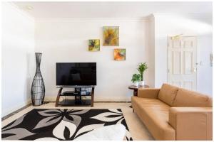 sala de estar con sofá y TV de pantalla plana en Charming, Cosy, Classic Executive 1 Bedroom Apartment en Perth