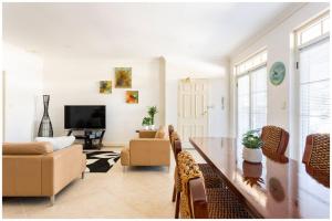 - un salon avec une table, des chaises et une télévision dans l'établissement Charming, Cosy, Classic Executive 1 Bedroom Apartment, à Perth