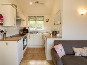 a small kitchen with white cabinets and a couch at Chalet Log Cabin L15 in Ilfracombe