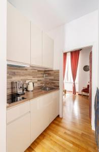 a kitchen with white cabinets and a wooden floor at Pantheon Caravaggio's House in Rome +14 photos