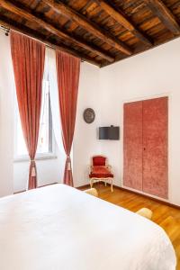a bedroom with a large bed and a red chair at Pantheon Caravaggio's House in Rome +14 photos